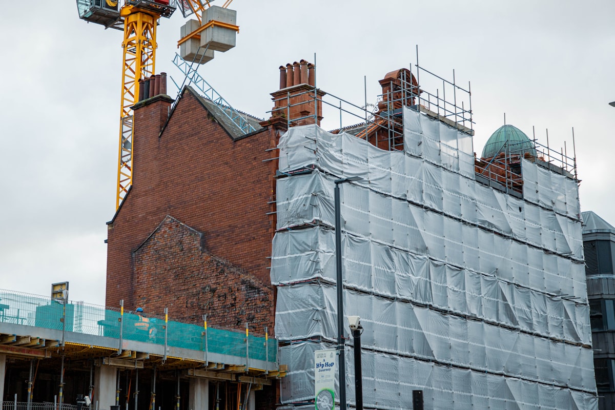 Wrapped building under renovation with scaffolding and tower crane