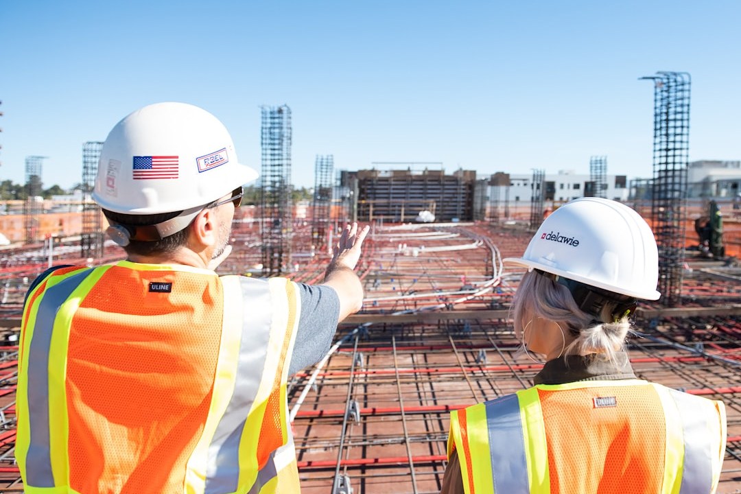 Two construction workers in safety vests and helmets on site