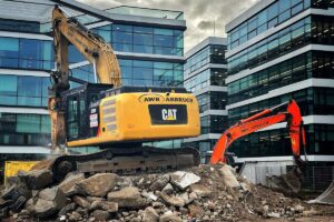 Excavator generating dust during demolition works next to office buildings