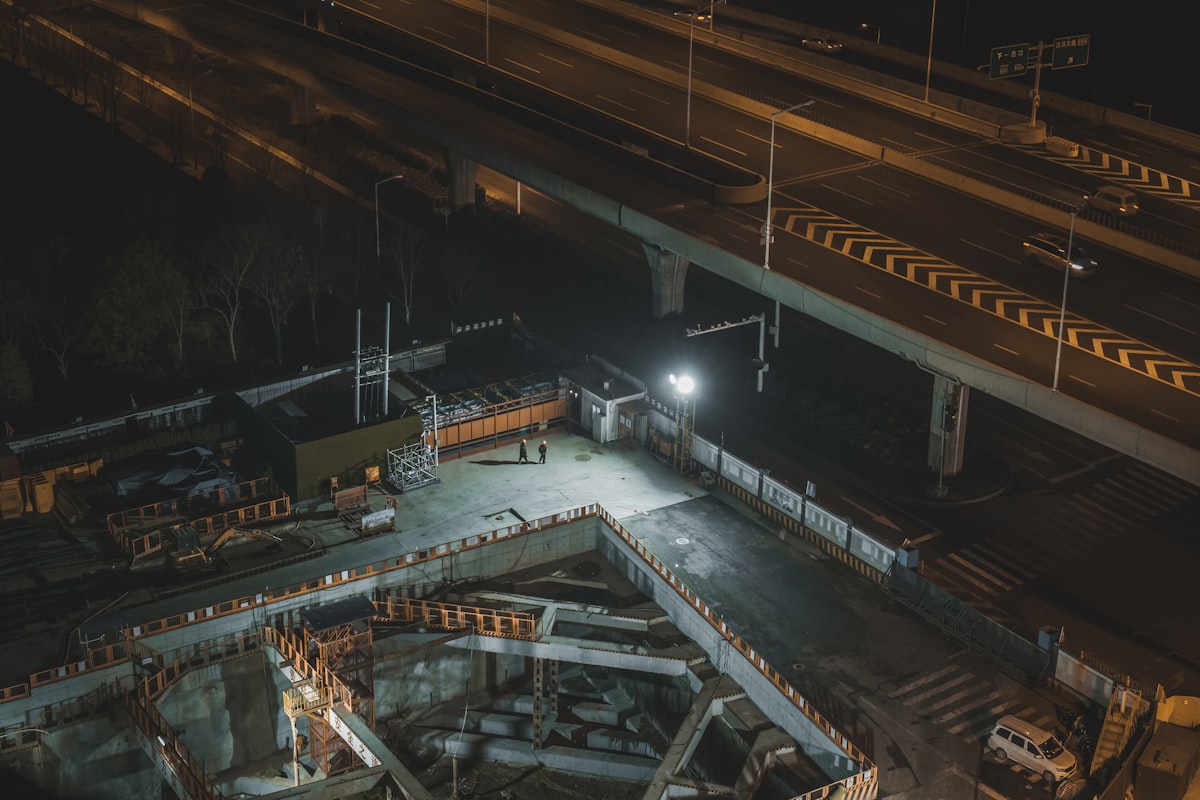 Construction excavation site working under floodlights at night